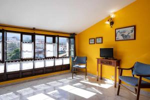PorrúaCasa rural El Cotero Lines的客厅拥有黄色的墙壁,配有电视和椅子