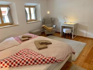 瓜尔达Grosszügige Komfort FEWO - ENGADIN HOLIDAYS的一间卧室配有两张床、一张桌子和一把椅子