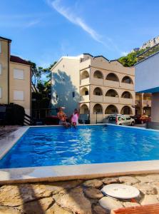 巴什卡沃达Apartments Vila Adrijana & Fitness Studio WOLF BV的两人坐在一个大型蓝色游泳池旁
