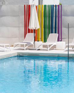 圣安东尼奥The Purple Hotel - Adults Only的一个带椅子和遮阳伞的游泳池和一个游泳池