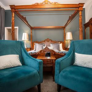 诺里奇Caistor Hall的一间卧室配有一张床和两张蓝色椅子