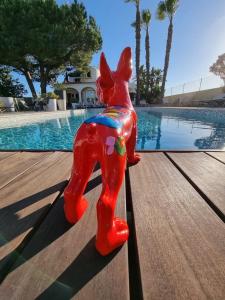 珀彻斯Casa Bela Moura, Boutique Hotel & Wine的坐在游泳池畔桌子上的红狗雕像