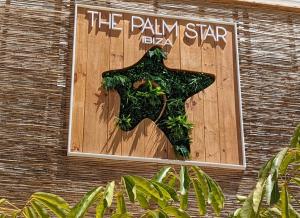 圣安东尼奥湾The Palm Star Ibiza - Adults Only的建筑物一侧的标志,有女人穿连衣裙