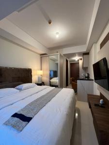 巴淡岛中心Meisterstadt Pollux Habibie Apartment by uhomeid的卧室配有一张白色大床和电视。