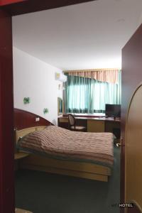 扎雷克MC Hotel的一间卧室配有一张带书桌的床和窗户。