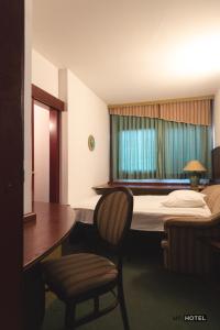 扎雷克MC Hotel的酒店客房,配有一张床、一张桌子和椅子