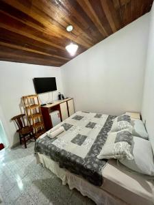 费尔南多 - 迪诺罗尼亚Pousada das Flores的一间卧室配有一张床、一张书桌和一台电视