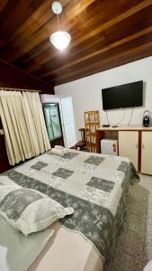 费尔南多 - 迪诺罗尼亚Pousada das Flores的一间卧室配有一张床和一张书桌及电视