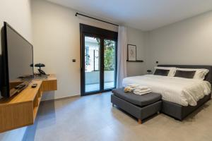 希俄斯Kaleo Chios Luxury Apartments的一间卧室配有一张床、一台电视和一把椅子