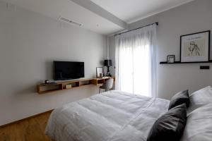 希俄斯Kaleo Chios Luxury Apartments的一间白色卧室,配有床和电视