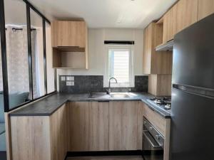 圣让-德蒙Superbe Mobil home 6-8 personnes (57)的厨房配有木制橱柜和不锈钢冰箱。
