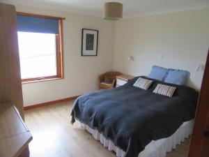 RosemarkieOsprey, Longhouse Cottages的一间卧室配有一张带蓝色床单的床和一扇窗户。