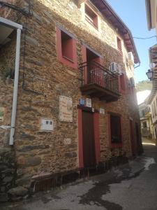 OvejuelaCasa Rural El Chorritero的一座砖砌建筑,设有红色的门和阳台