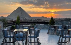 开罗Kemet Boutique Hotel的一个带桌椅和金字塔的庭院