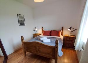 戈尔韦Cosy Cottage by the Sea的一间卧室配有一张木床和两盏灯。