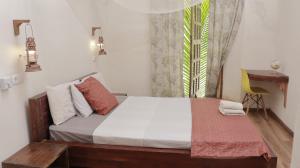 莫桑比克岛Cafe Central的一间卧室配有一张带书桌的床和窗户。