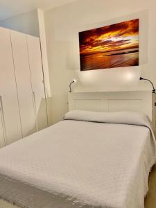 葛伦坦马勒NOVELLA DEL MAR prima fila dal mare的卧室配有一张白色床,墙上挂有绘画作品