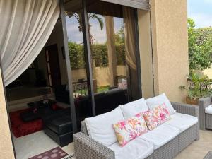 马拉喀什Marrakech le joyau Big villa piscine privée jardin的庭院内一张带两个枕头的白色沙发