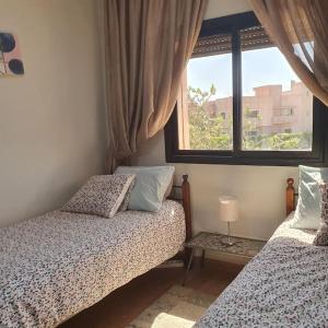 马拉喀什Marrakech le joyau Big villa piscine privée jardin的一间卧室设有两张床和窗户。