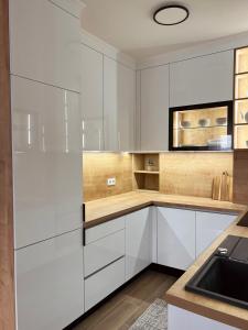萨拉热窝Luxury Apartment Kadic的白色的厨房配有白色橱柜和水槽