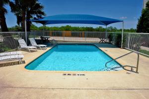 圣安东尼奥圣安东尼奥市区阿拉莫圆顶体育馆6号汽车旅馆的一个带蓝伞和椅子的游泳池