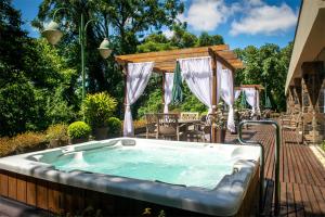 格拉玛多Villa Bella Hotel & SPA Gramado的庭院内的热水浴池,配有桌椅