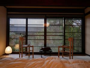 松本Satoyama villa DEN - Vacation STAY 14150的一间卧室配有两把椅子和一张床,并设有大窗户