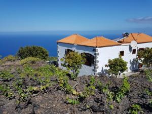丰卡连特德拉帕尔马House the Viñas 2 With views of the sea, the mountains and the volcanoes的一座山丘上的房屋,背景是大海