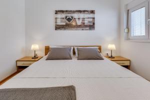 佩特坎内Apartments Juraj的一间卧室配有一张带两盏灯的大型白色床。