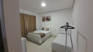 卡皮托利乌Pousada Jeitim Mineiro的一间白色的小房间,配有床和梳妆台