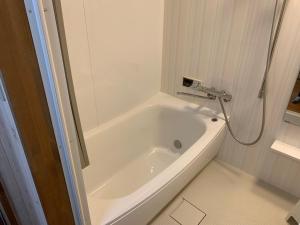 近江八幡市Guesthouse Shin的带淋浴的浴室配有白色浴缸。