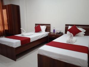古瓦哈提HOTEL HAREN GRAND的一间卧室配有两张红色和白色床单
