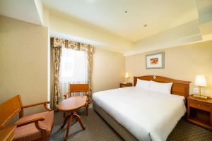 名古屋KOKO Hotel Nagoya Sakae的酒店客房,配有一张床、一张桌子和椅子