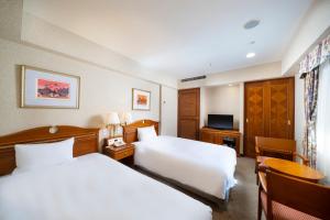 名古屋KOKO Hotel Nagoya Sakae的酒店客房设有两张床和电视。
