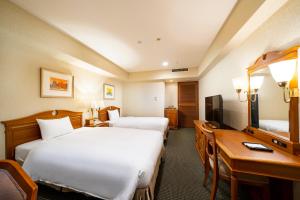 名古屋KOKO Hotel Nagoya Sakae的酒店客房配有两张床和一张书桌