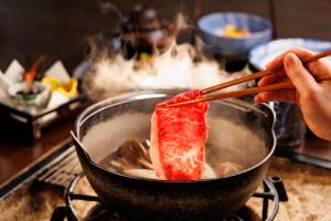 驹根市山吹旅馆的一个人在 ⁇ 里用筷子挑食物