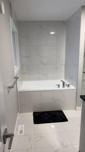 埃德蒙顿3 Bedroom Single Family Home的白色的浴室设有浴缸和黑色地毯。