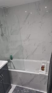 伦敦Transom Close的一间带白色浴缸及玻璃墙的浴室