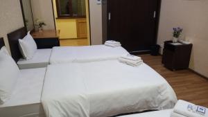 塔什干海特旅馆的配有白色床单的酒店客房内的两张床