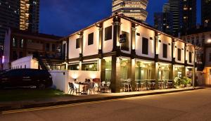 新加坡Dream Chaser Boutique Capsule Hotel的街上的一座带桌椅的建筑