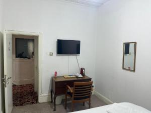 依尔福Saji Hotel Illford的一间房间,配有一张桌子和一台墙上的电视