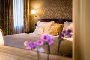 威尼斯卡玛丽亚阿黛尔旅馆的一间卧室,床上有紫色鲜花