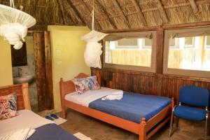 马赛马拉Giraffe Hills Mara Camp的一间卧室配有一张床、一把椅子和窗户。