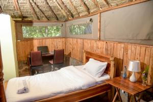 马赛马拉Giraffe Hills Mara Camp的一间卧室配有一张床、一张桌子和一张桌子