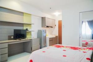 KemplangBandara City Apartment Near Bandara Soekarno Hatta - Type Studio的一间卧室配有一张床和一张书桌及电视