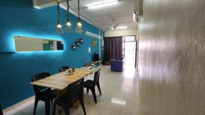 士姑来Guest House at Johor Bahru的一间设有木桌和蓝色墙壁的用餐室