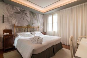 蒙特格罗托泰梅Terme Preistoriche Resort & Spa的一间卧室配有一张带白色床单的大床