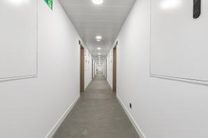 马德里micampus Madrid Sinesio Delgado Student Residence的一条有白色墙壁和长走廊的走廊