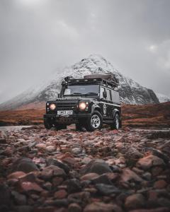 莫珀斯Land Rover Defender Luxury Camper的停在雪覆盖的山前的吉普车