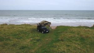 莫珀斯Land Rover Defender Luxury Camper的停在海边的卡车